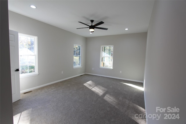 carpeted spare room featuring ceiling fan and plenty of natural light