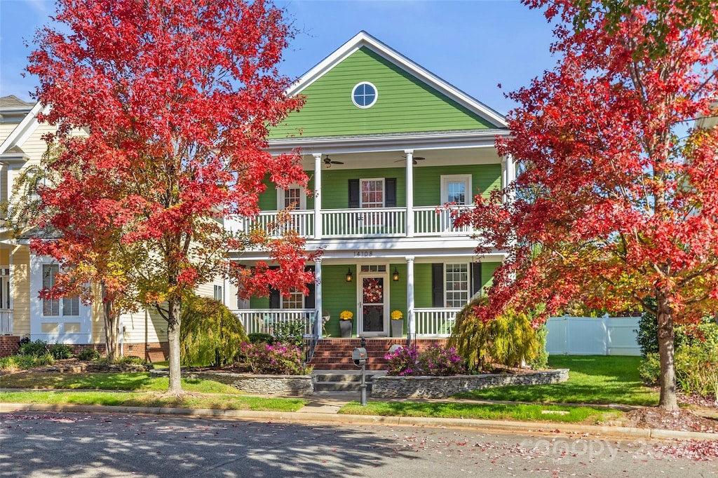 view of front of home featuring covered porch, a balcony, and a front yard