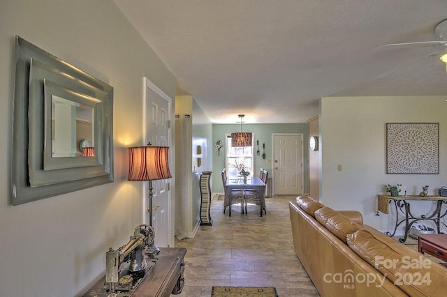 living room featuring ceiling fan and a textured ceiling