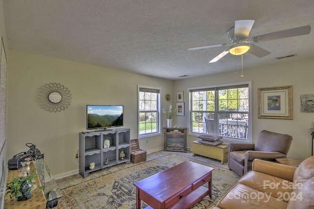 living room with a textured ceiling and ceiling fan