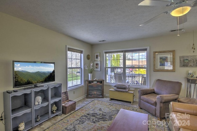 living room featuring ceiling fan and a textured ceiling