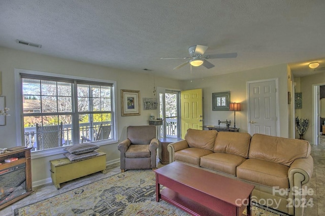 living room with ceiling fan and a textured ceiling