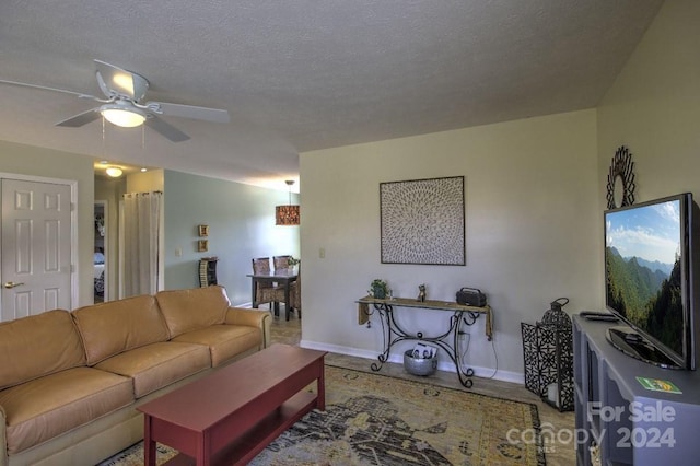 living room featuring ceiling fan and a textured ceiling