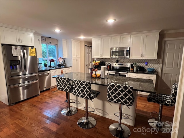 kitchen featuring an island with sink, dark hardwood / wood-style flooring, white cabinetry, and appliances with stainless steel finishes