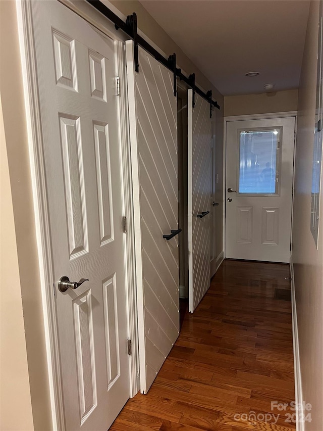 corridor with dark hardwood / wood-style flooring and a barn door