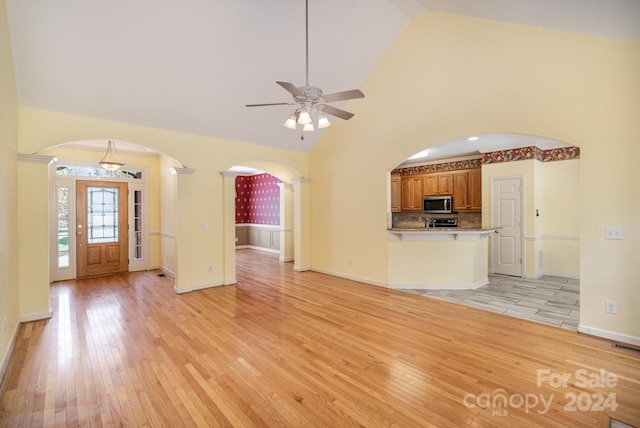 unfurnished living room with high vaulted ceiling, light hardwood / wood-style flooring, and ceiling fan