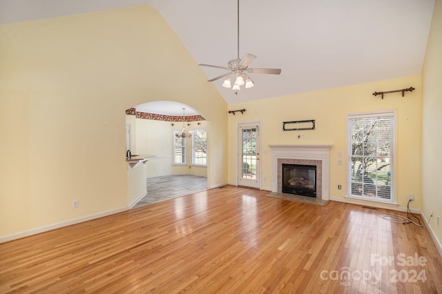 unfurnished living room with high vaulted ceiling, light wood-type flooring, ceiling fan, and a fireplace