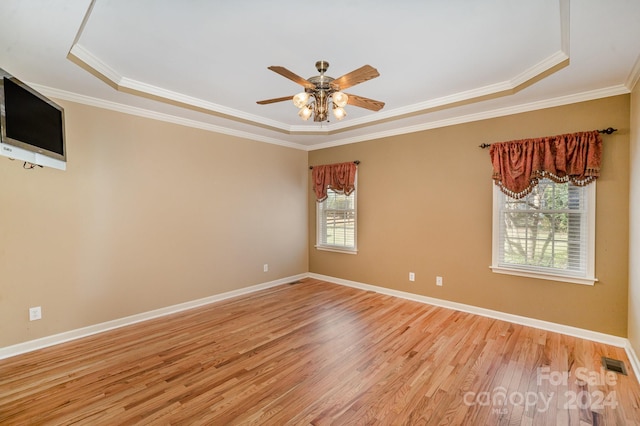 unfurnished room featuring light wood-type flooring, a tray ceiling, ceiling fan, and ornamental molding