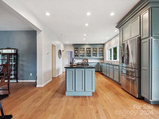 kitchen with light hardwood / wood-style floors, sink, stainless steel fridge, and a center island