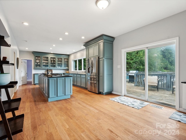 kitchen with light hardwood / wood-style floors, sink, a kitchen island, and stainless steel fridge with ice dispenser