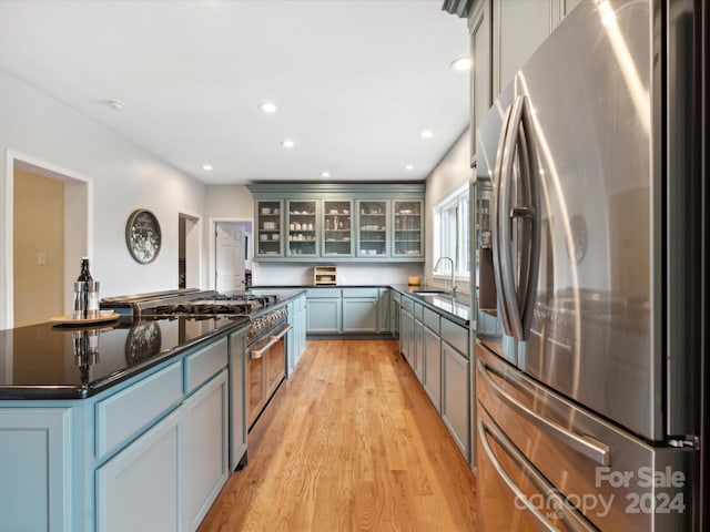 kitchen featuring stainless steel appliances, a kitchen island, gray cabinets, sink, and light hardwood / wood-style flooring