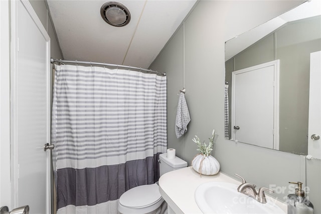 bathroom with toilet, vanity, and vaulted ceiling