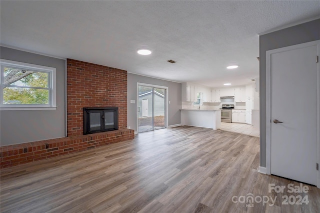 unfurnished living room with a wealth of natural light, a textured ceiling, light hardwood / wood-style floors, and a fireplace