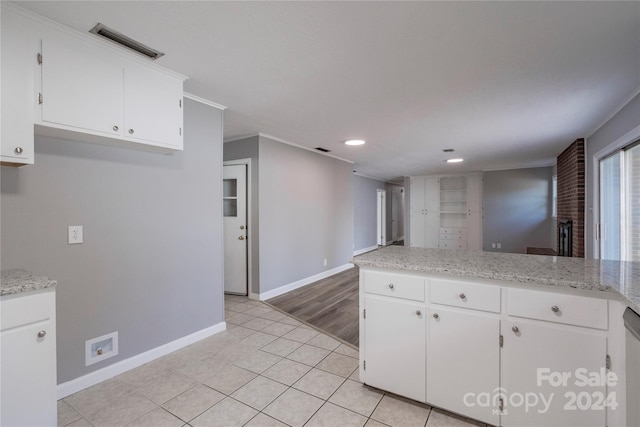 kitchen featuring stainless steel dishwasher, light stone counters, light tile patterned floors, and white cabinets