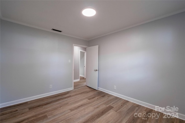 empty room featuring light wood-type flooring and ornamental molding