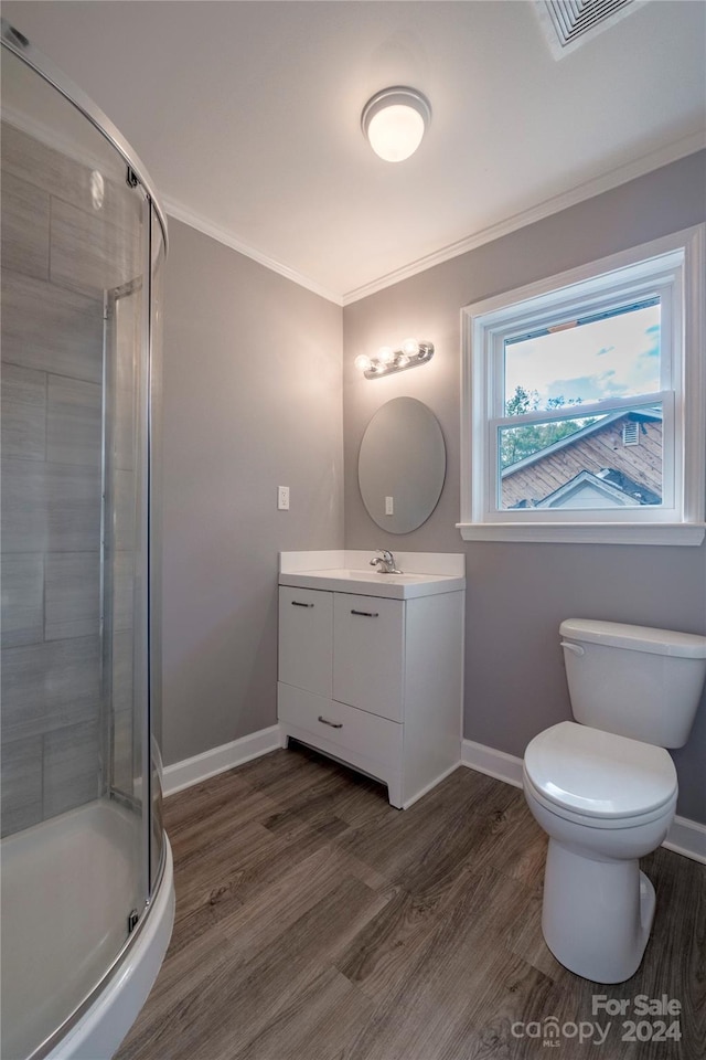 bathroom featuring wood-type flooring, vanity, a shower with shower door, and ornamental molding