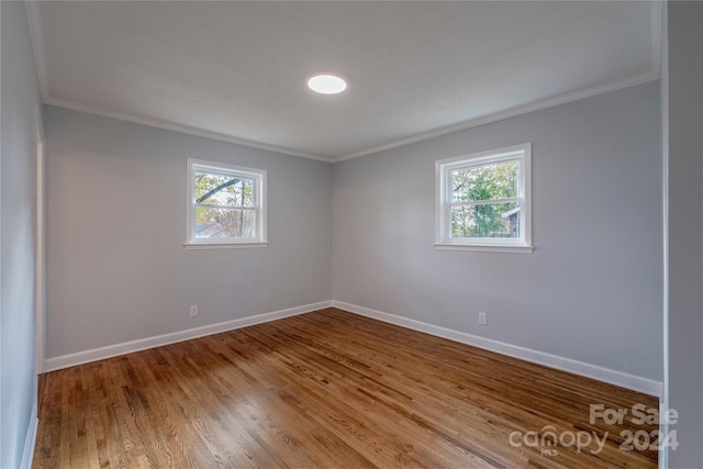 empty room with wood-type flooring and crown molding