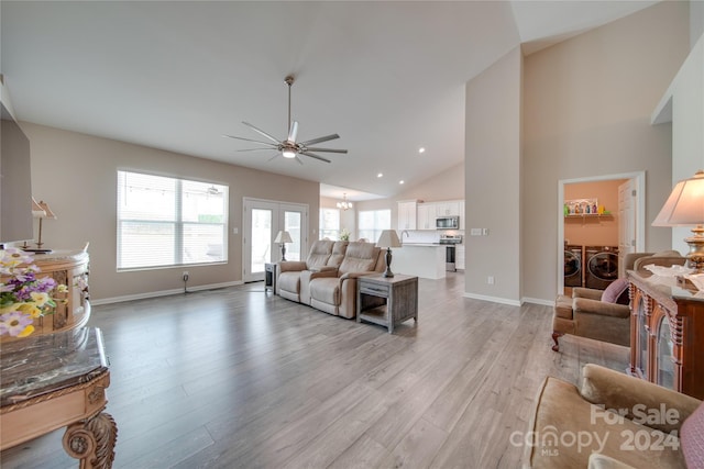 living room featuring light hardwood / wood-style floors, ceiling fan, high vaulted ceiling, and independent washer and dryer