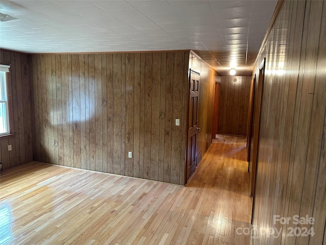 spare room with light wood-type flooring and wooden walls