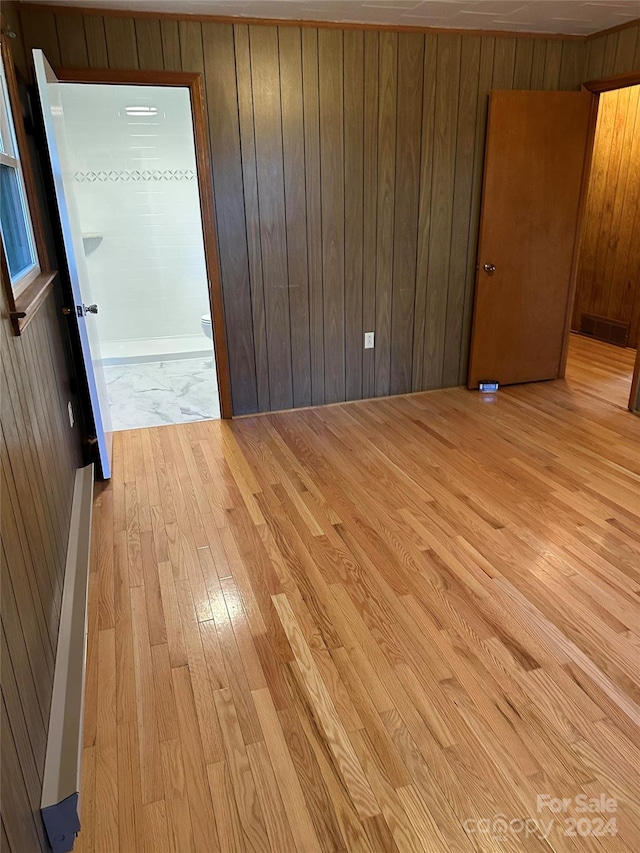 unfurnished room featuring light wood-type flooring and wooden walls