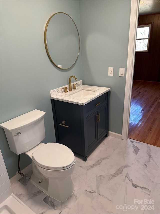 bathroom with wood walls, hardwood / wood-style flooring, vanity, and toilet