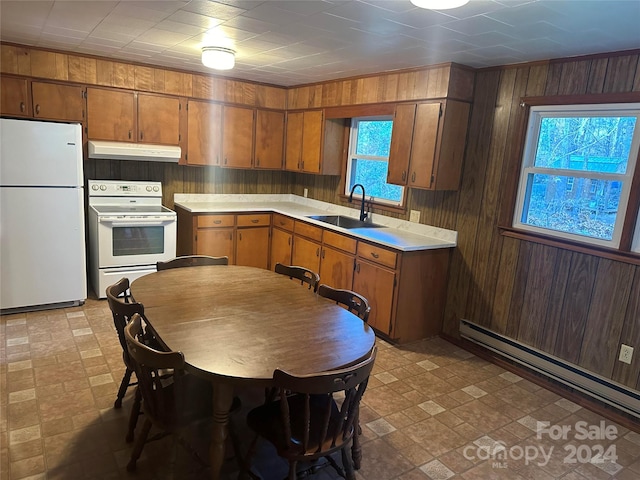 kitchen featuring a baseboard heating unit, wood walls, sink, and white appliances