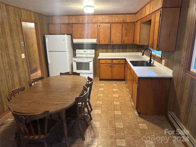 kitchen featuring a baseboard heating unit, wood walls, sink, and white appliances