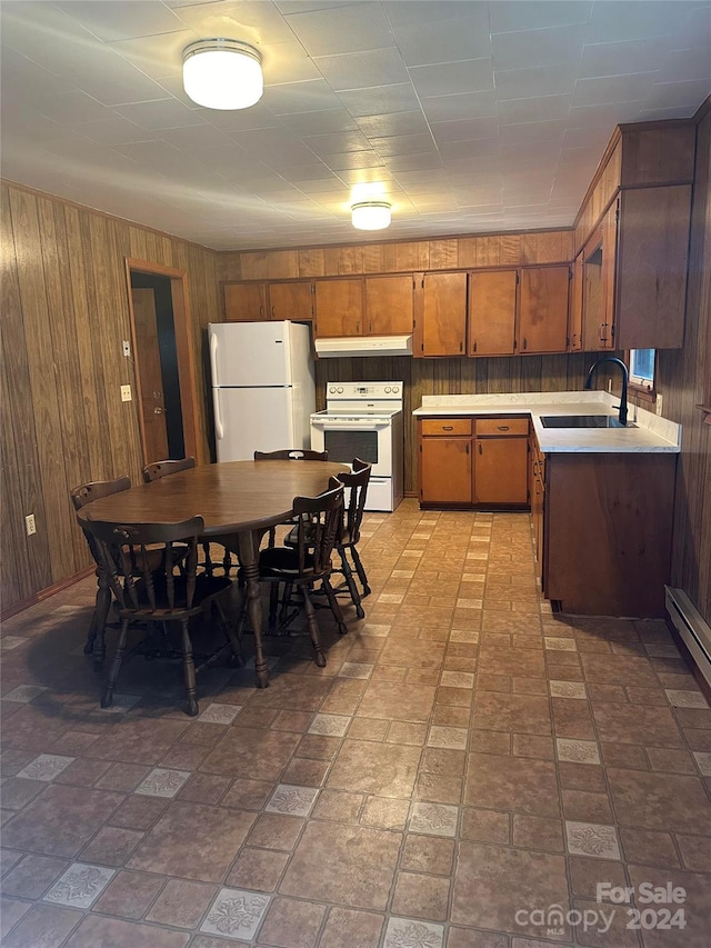 kitchen featuring wood walls, white appliances, and sink