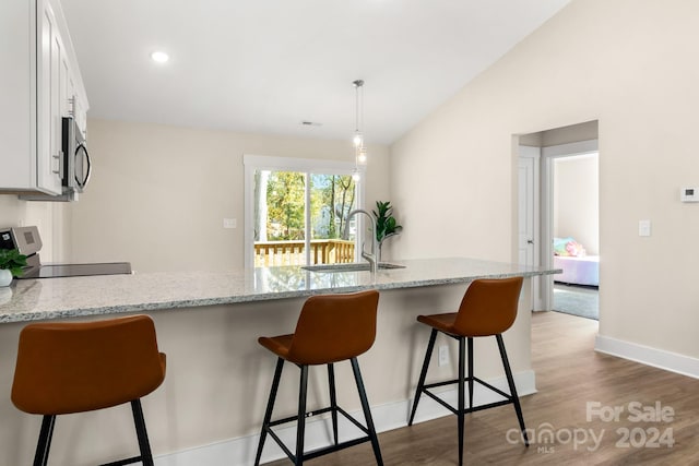 kitchen featuring stove, sink, hanging light fixtures, light stone countertops, and white cabinetry