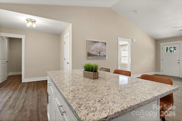 kitchen featuring a kitchen breakfast bar, white cabinetry, lofted ceiling, and hardwood / wood-style flooring