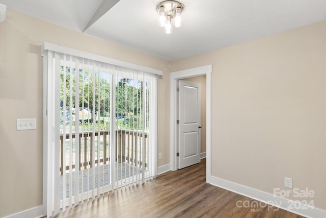 unfurnished room featuring dark hardwood / wood-style floors and vaulted ceiling