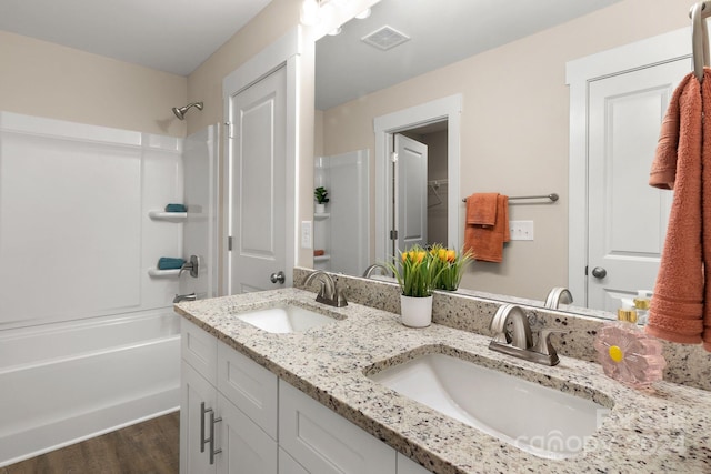 bathroom with hardwood / wood-style floors, vanity, and shower / bath combination