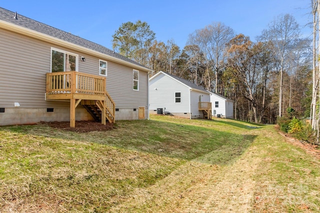 rear view of property featuring a wooden deck, a yard, and central AC