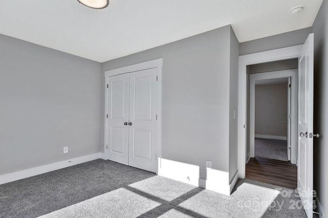 unfurnished bedroom with dark carpet and a closet