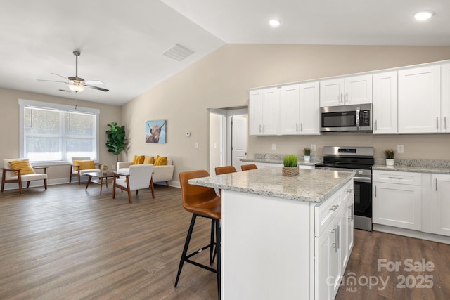 121 Orchard St, Forest City, NC 28043 - kitchen featuring a kitchen island, a kitchen breakfast bar, dark wood-style floors, appliances with stainless steel finishes, and vaulted ceiling