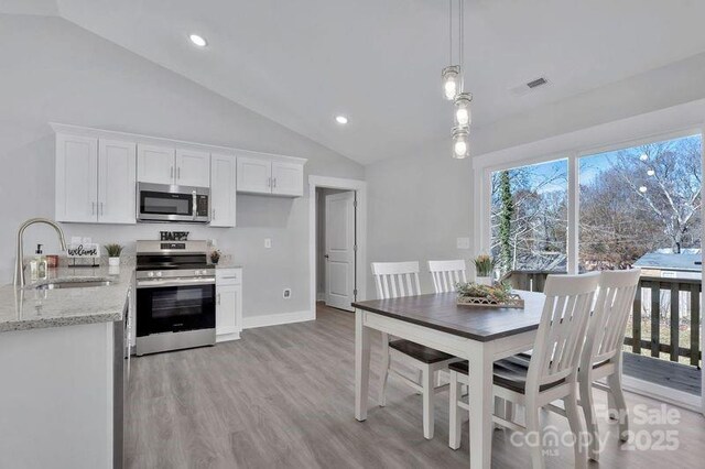 135 Orchard St, Forest City, NC 28043 - kitchen featuring white cabinets, light stone counters, a sink, stainless steel appliances, and lofted ceiling
