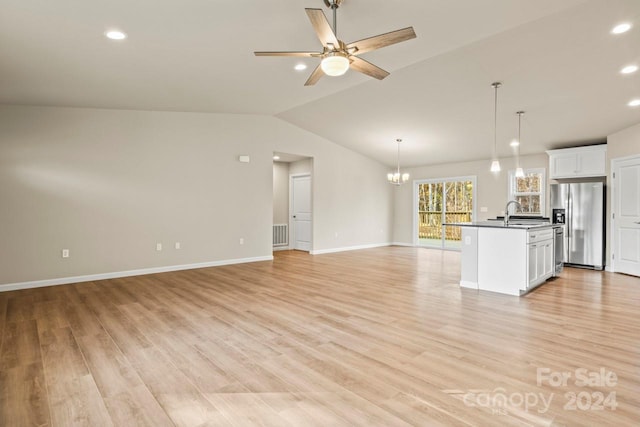 unfurnished living room with sink, ceiling fan with notable chandelier, light hardwood / wood-style floors, and lofted ceiling