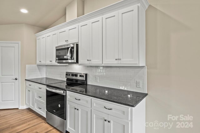 kitchen featuring white cabinetry, tasteful backsplash, dark stone countertops, light hardwood / wood-style floors, and appliances with stainless steel finishes