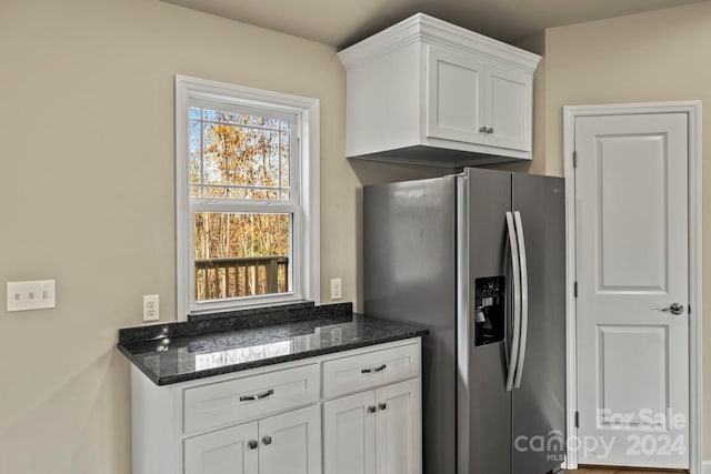 kitchen featuring white cabinetry, a wealth of natural light, stainless steel fridge with ice dispenser, and dark stone countertops