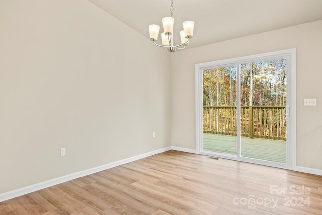 empty room featuring light hardwood / wood-style floors and a notable chandelier