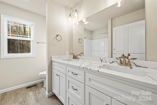 bathroom featuring toilet, hardwood / wood-style floors, vanity, and walk in shower