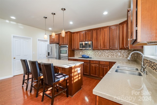 kitchen with a center island, dark wood-type flooring, sink, a kitchen bar, and stainless steel appliances