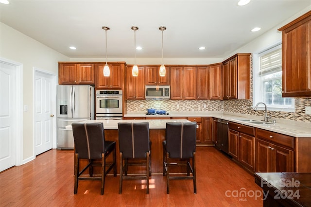 kitchen featuring sink, stainless steel appliances, dark hardwood / wood-style floors, pendant lighting, and a kitchen island