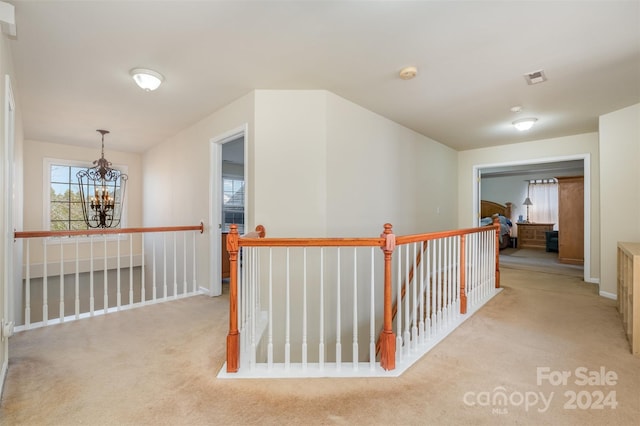 hallway featuring a chandelier and light colored carpet