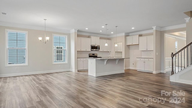 kitchen with light wood-type flooring, pendant lighting, a center island with sink, and stainless steel appliances