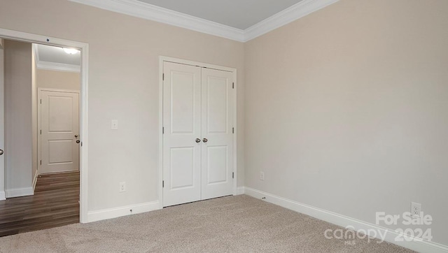 unfurnished bedroom with carpet floors, crown molding, and a closet