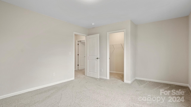 unfurnished bedroom with light carpet, a closet, and a walk in closet