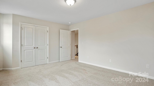 unfurnished bedroom featuring light carpet and a closet