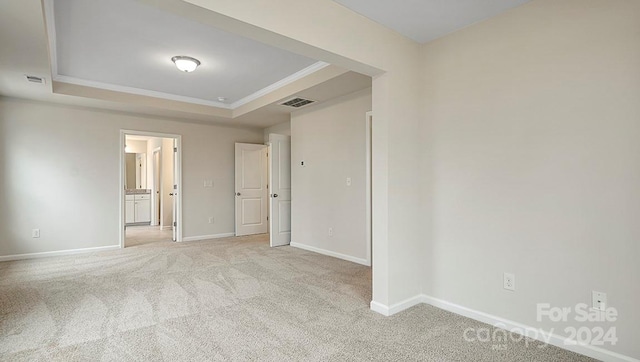 unfurnished room featuring light carpet, ornamental molding, and a raised ceiling