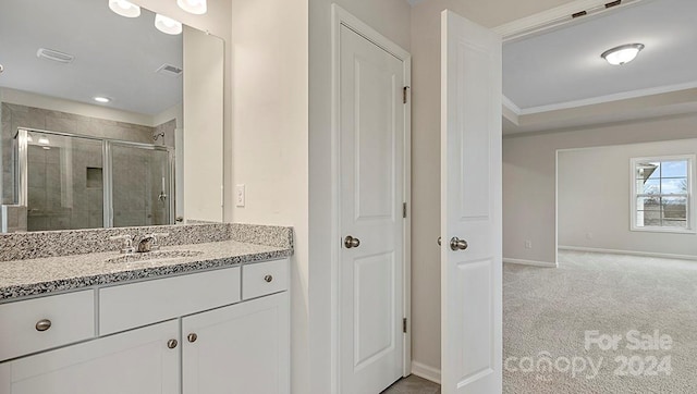 bathroom featuring vanity, a shower with door, and ornamental molding